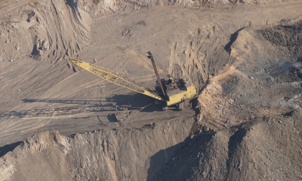 aerial view of open pit mine, with an excavator pictured in the middle