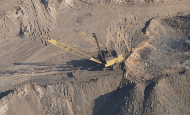 aerial view of open pit mine, with an excavator pictured in the middle